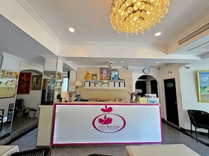 A reception desk with a logo, a chandelier, framed pictures, and a clock on the wall. - Orchid Hotel and Spa Kalim Bay (Patong)