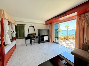 A hotel room with a desk, chair, and a large mirror. There is a sliding glass door leading to a balcony with a checkered floor and potted plants. - Orchid Hotel and Spa Kalim Bay (Patong)