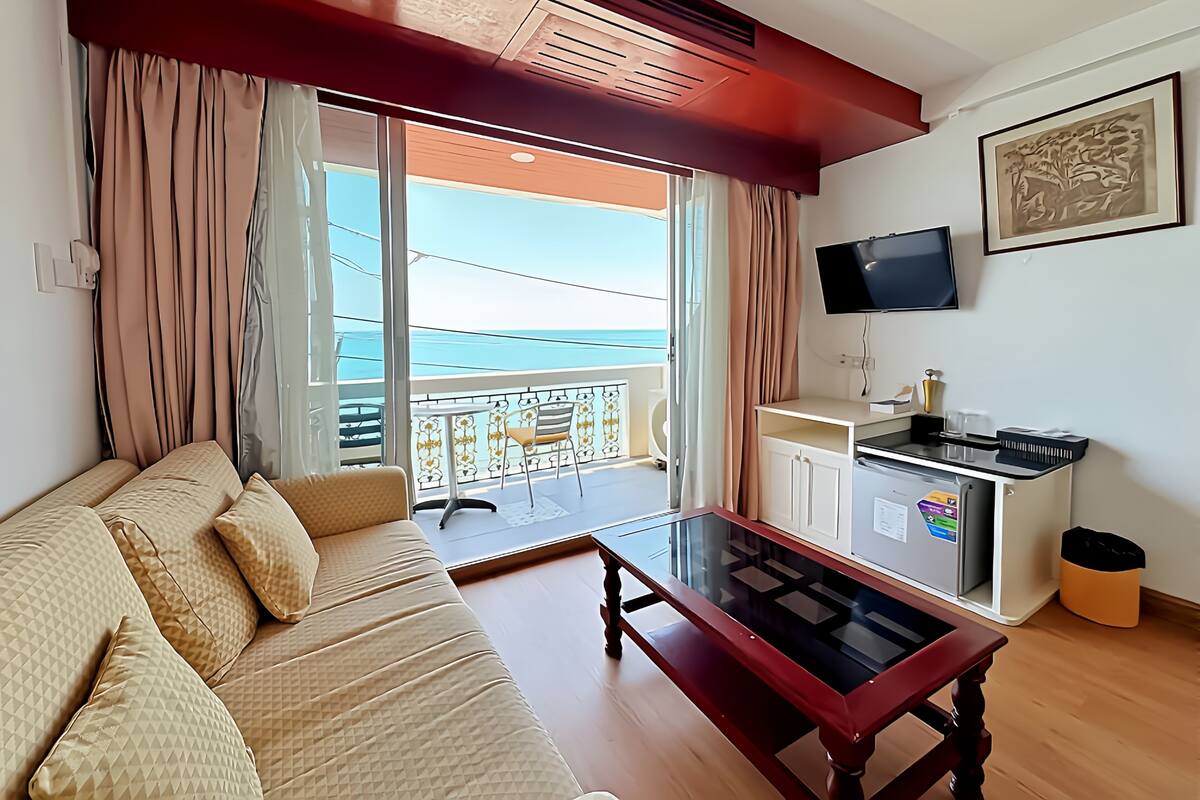 Ein Wohnzimmer mit einer Couch, einem Couchtisch, einem Fernseher und einem Balkon mit Blick.