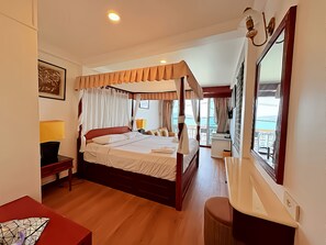 A bedroom with a four-poster bed, bedside lamps, a desk, and a view of the sea. - Orchid Hotel and Spa Kalim Bay (Patong)