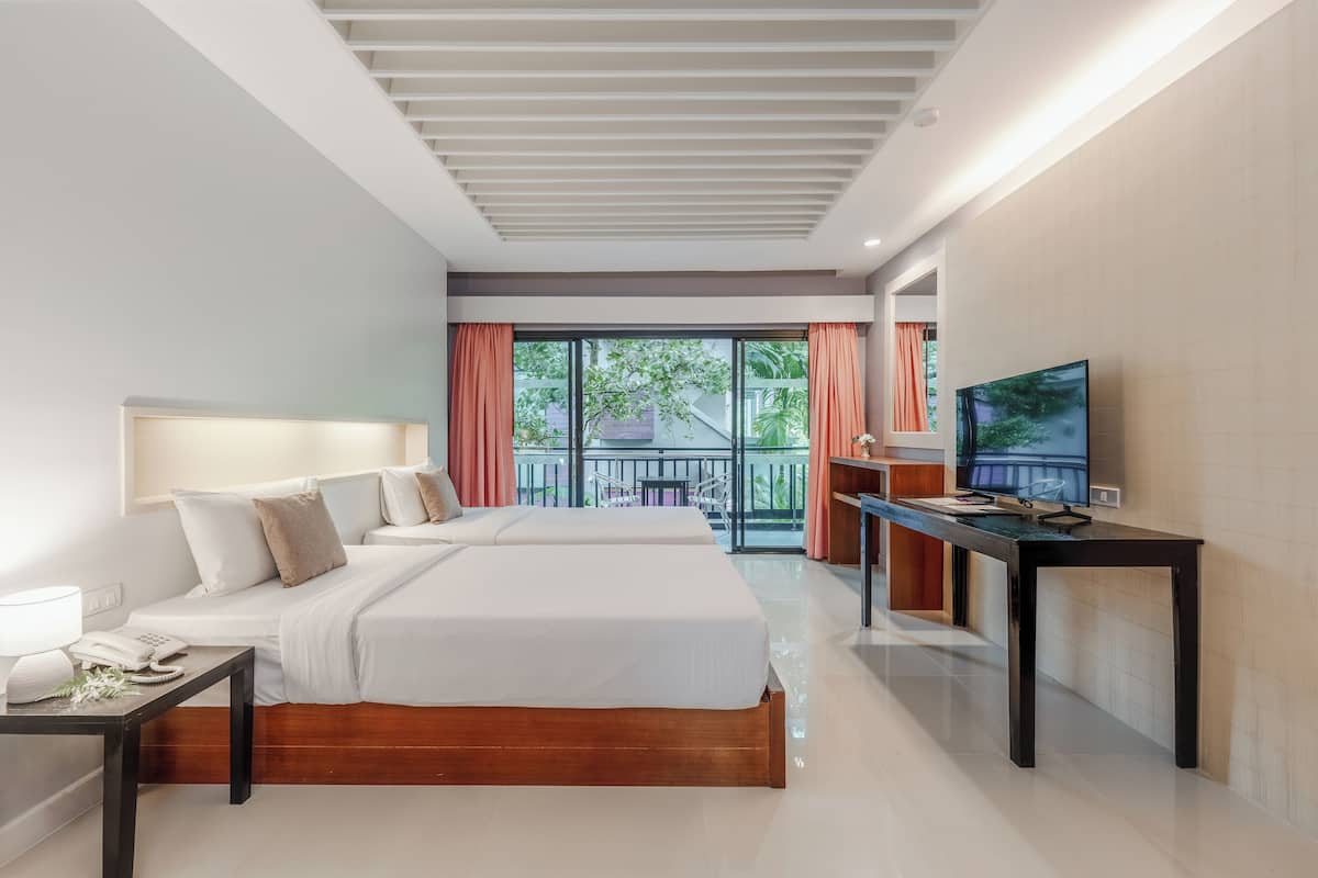 Et moderne hotelværelse med to senge, et skrivebord med et fjernsyn og en balkon med orange gardiner.