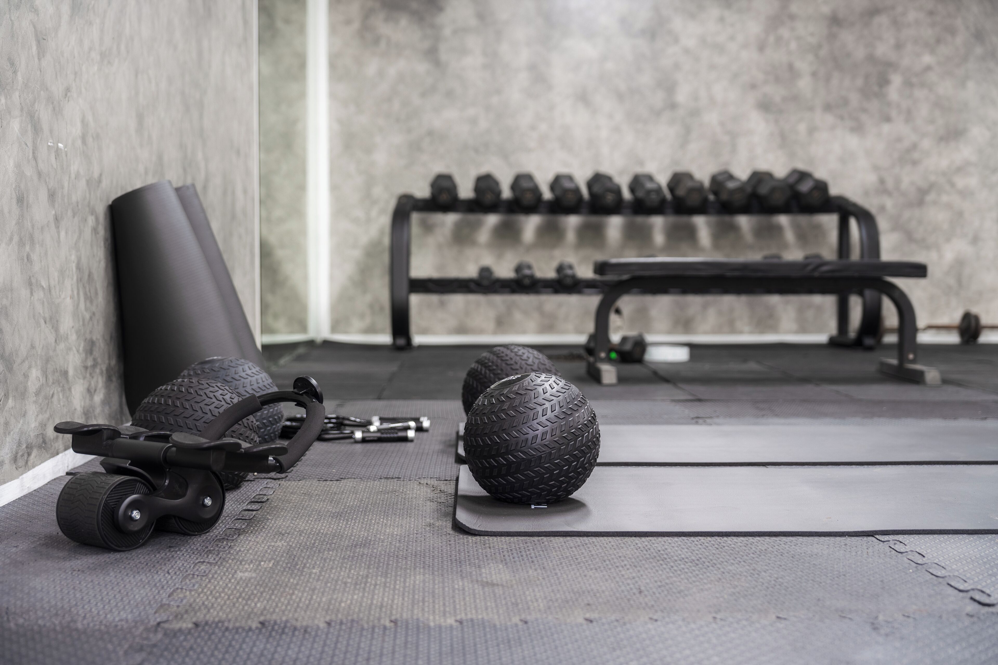 Une salle de sport équipée de matériel d’exercice, notamment un pneu, un vélo entraîné par un pneu et un banc.
