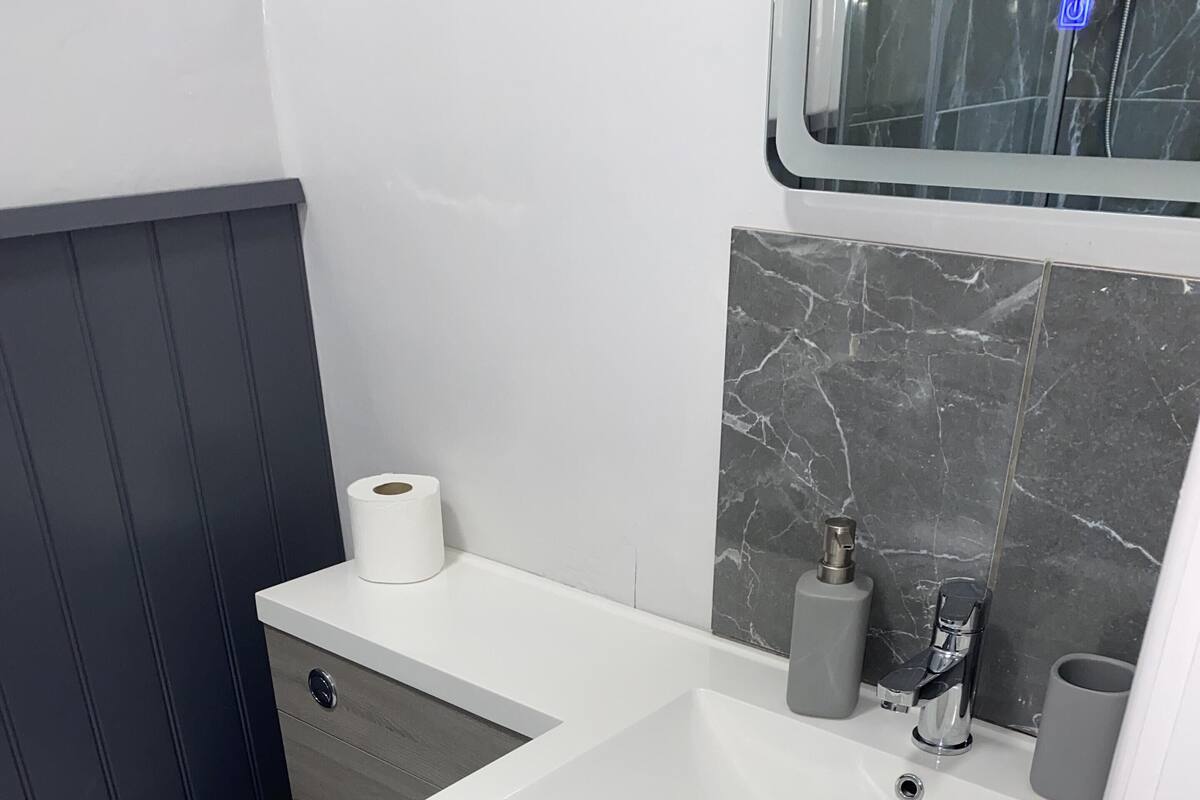 A compact bathroom with a white sink, a toilet, and a vanity with drawers.