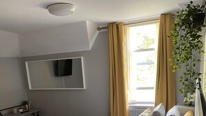 A hotel room with two beds, a desk, a TV, and a window with curtains. - The Hall Park Hotel (Workington)