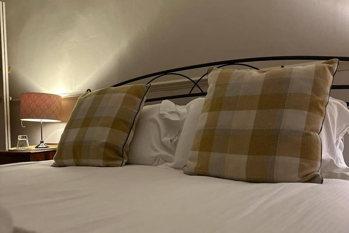 A neatly made bed with checkered pillows and a white comforter.