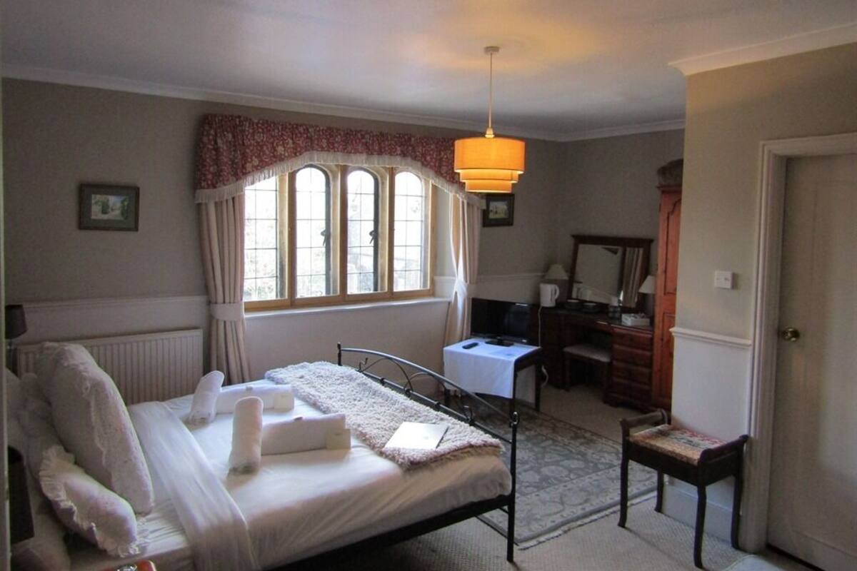 A neatly arranged bedroom with a bed, a desk, and a chair.