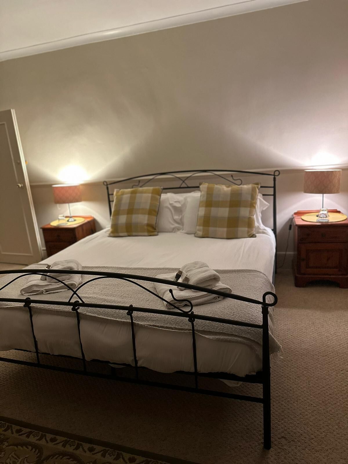 A bed with a metal frame, two pillows, and a bedside table with a lamp.