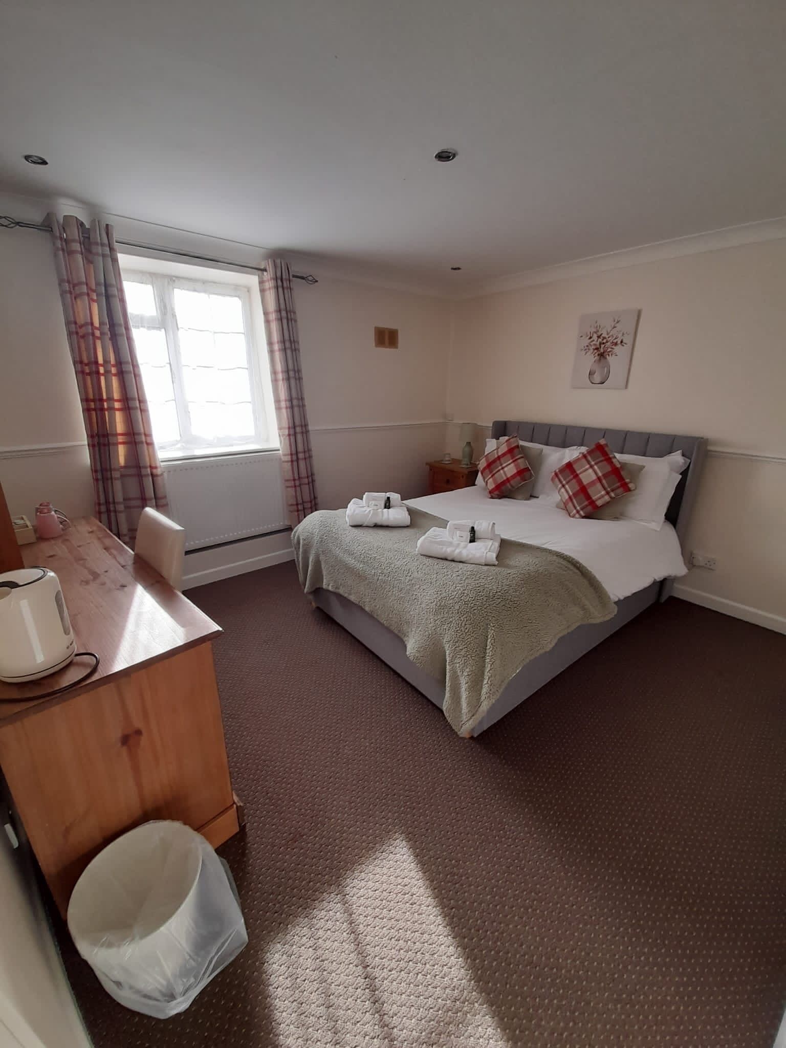 A neatly arranged bedroom with a bed, bedside table, and a window with curtains.