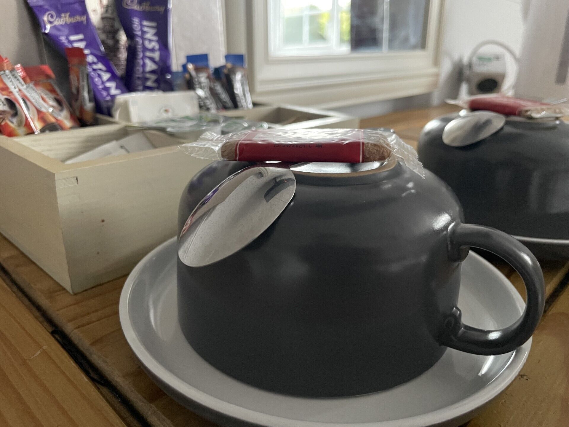 Un área de cocina con un juego de té sobre una mesa de madera, incluyendo una tetera y tazas.