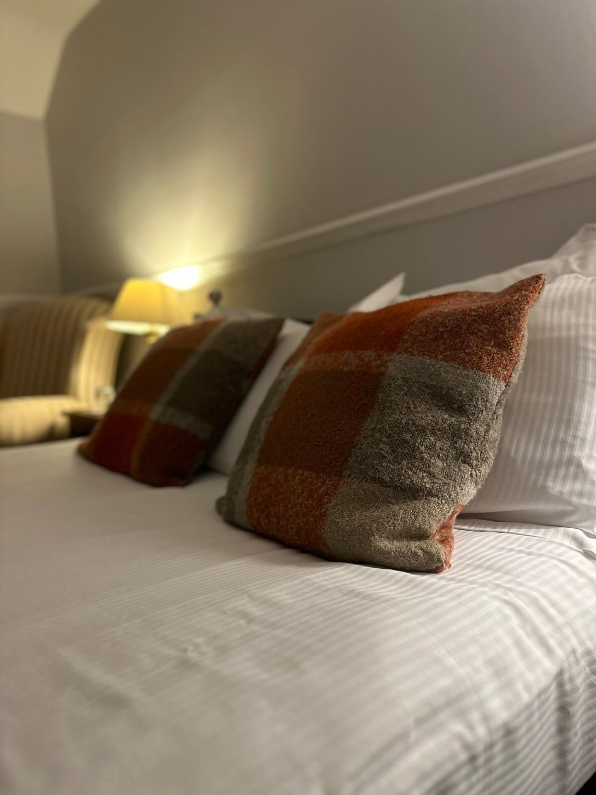 Una cama con ropa de cama a rayas y tres almohadas de estampado cuadriculado.