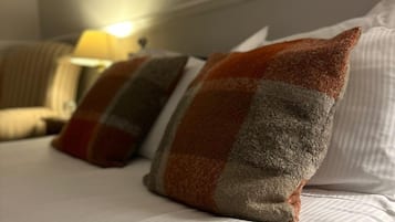 Cama com roupa de cama listrada e três almofadas estampadas em xadrez.