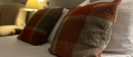 Una cama con ropa de cama a rayas y tres almohadas de estampado cuadriculado.