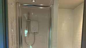 Een moderne badkamer met een douchecabine van glas, een toilet en een wastafel.