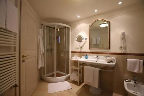 A bathroom with a glass-enclosed shower, a sink with a mirror, and a bidet.