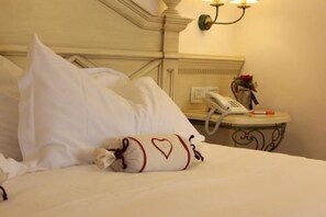 A hotel room with a neatly made bed, a bedside telephone, and a wall-mounted light fixture.