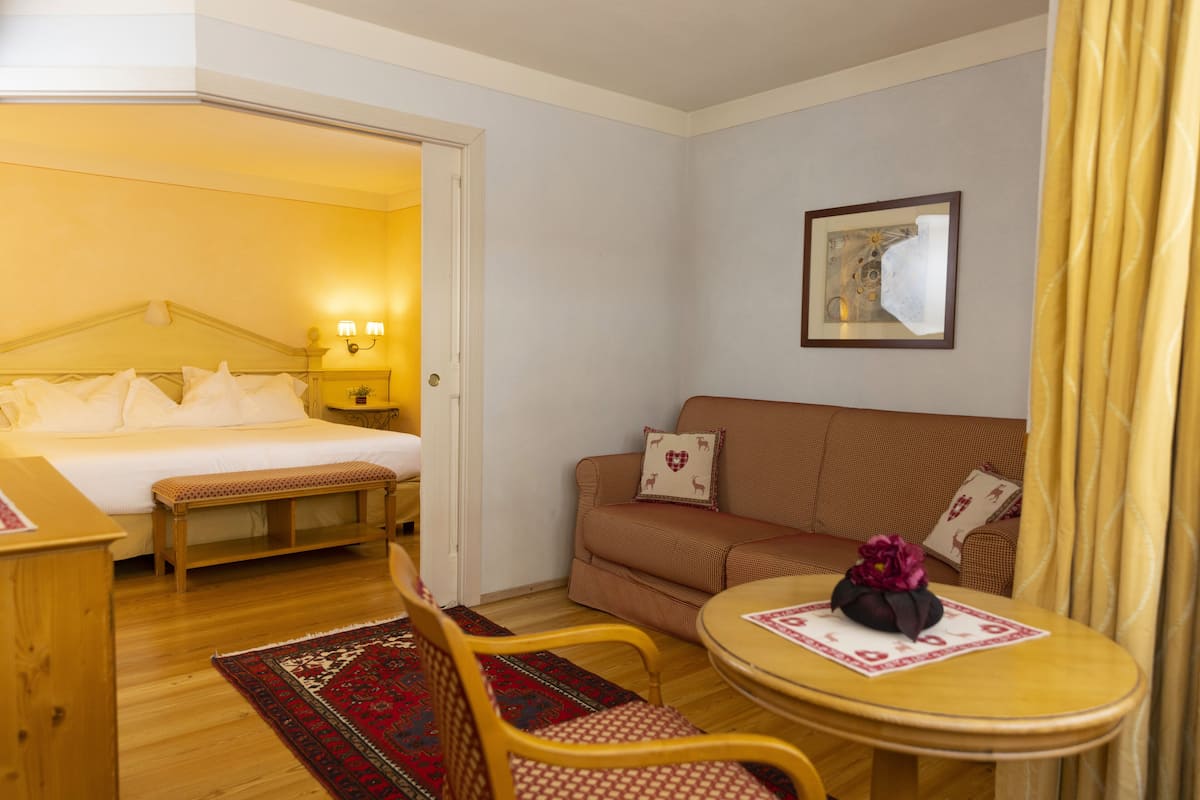 Una habitación de hotel con una cama, un sofá, una mesita y una banca.
