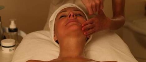 Una persona acostada con una toalla en la cabeza, recibiendo un tratamiento facial.