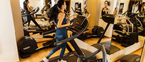 A gym with treadmills, exercise equipment, and mirrors.