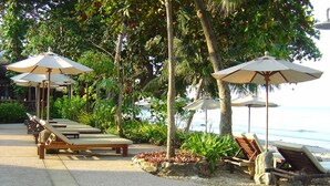 A beachside resort with sun loungers and umbrellas, a pebble beach, and a view of the ocean. - Banpu Koh Chang (Ko Chang)