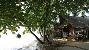 A beachfront property with a thatched-roof house, a wooden deck, and a sandy beach. - Banpu Koh Chang (Ko Chang)