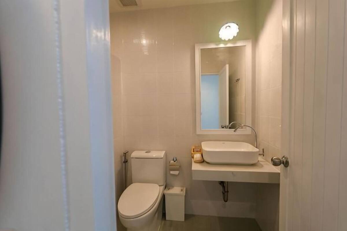 A bathroom with a toilet, sink, and mirror.