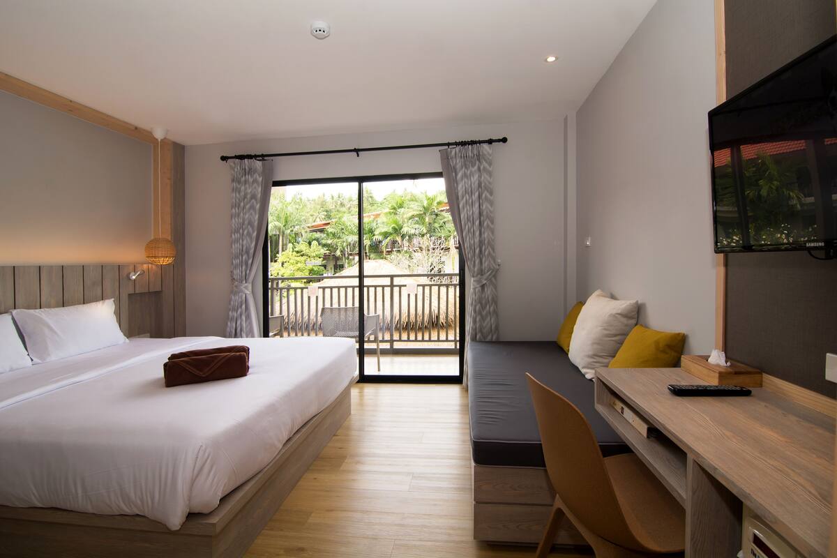 A hotel room with a bed, desk, chair, and a TV.