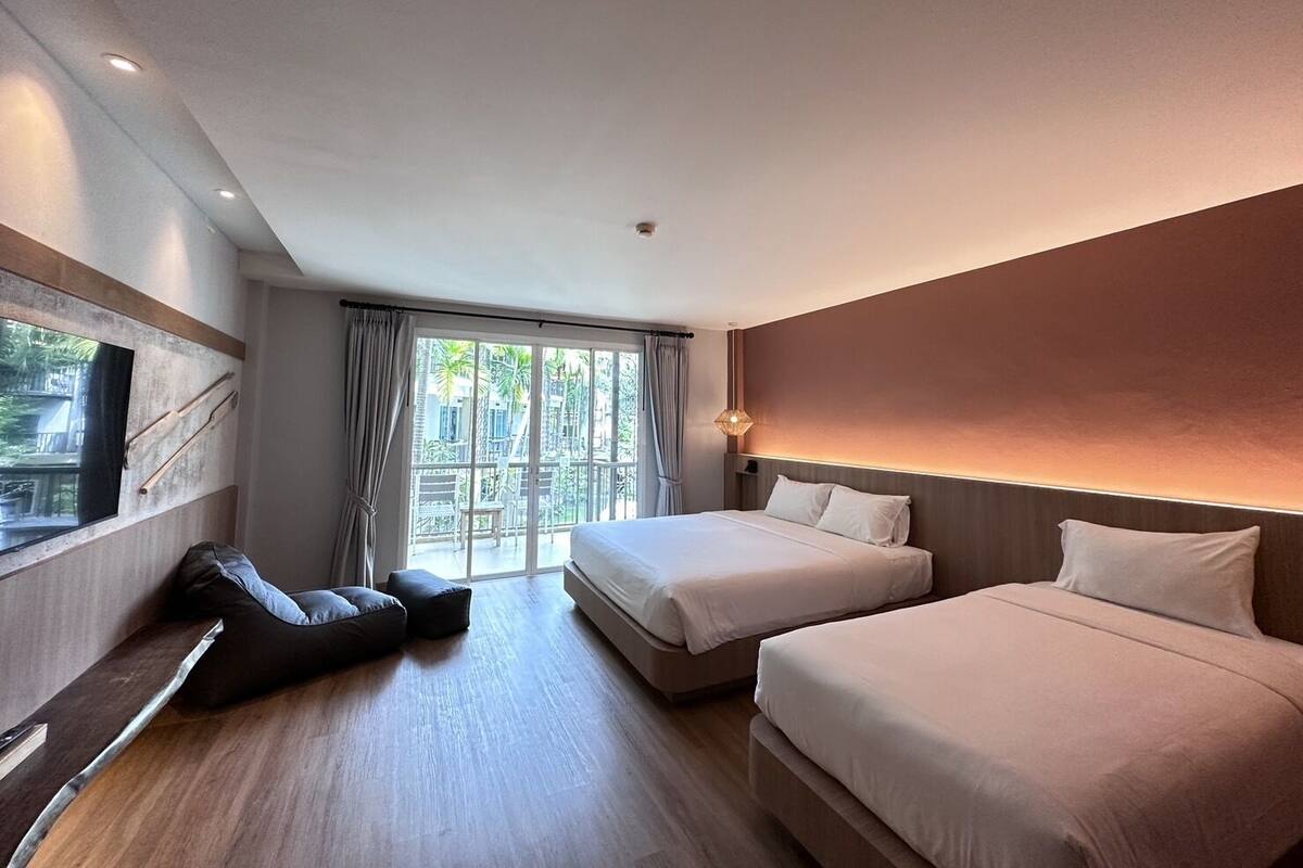 A modern hotel room with two beds, a large window, and a balcony.