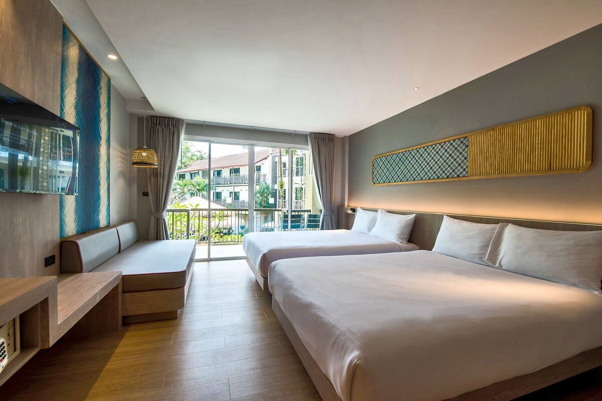 A modern hotel room with a large bed, a seating area, and a balcony with a view of the city.