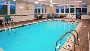 Una piscina con agua cristalina, rodeada de sillas de descanso y una estación de socorristas.