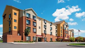 Un hotel de varios pisos con fachada de ladrillo, múltiples ventanas y un cielo azul despejado.