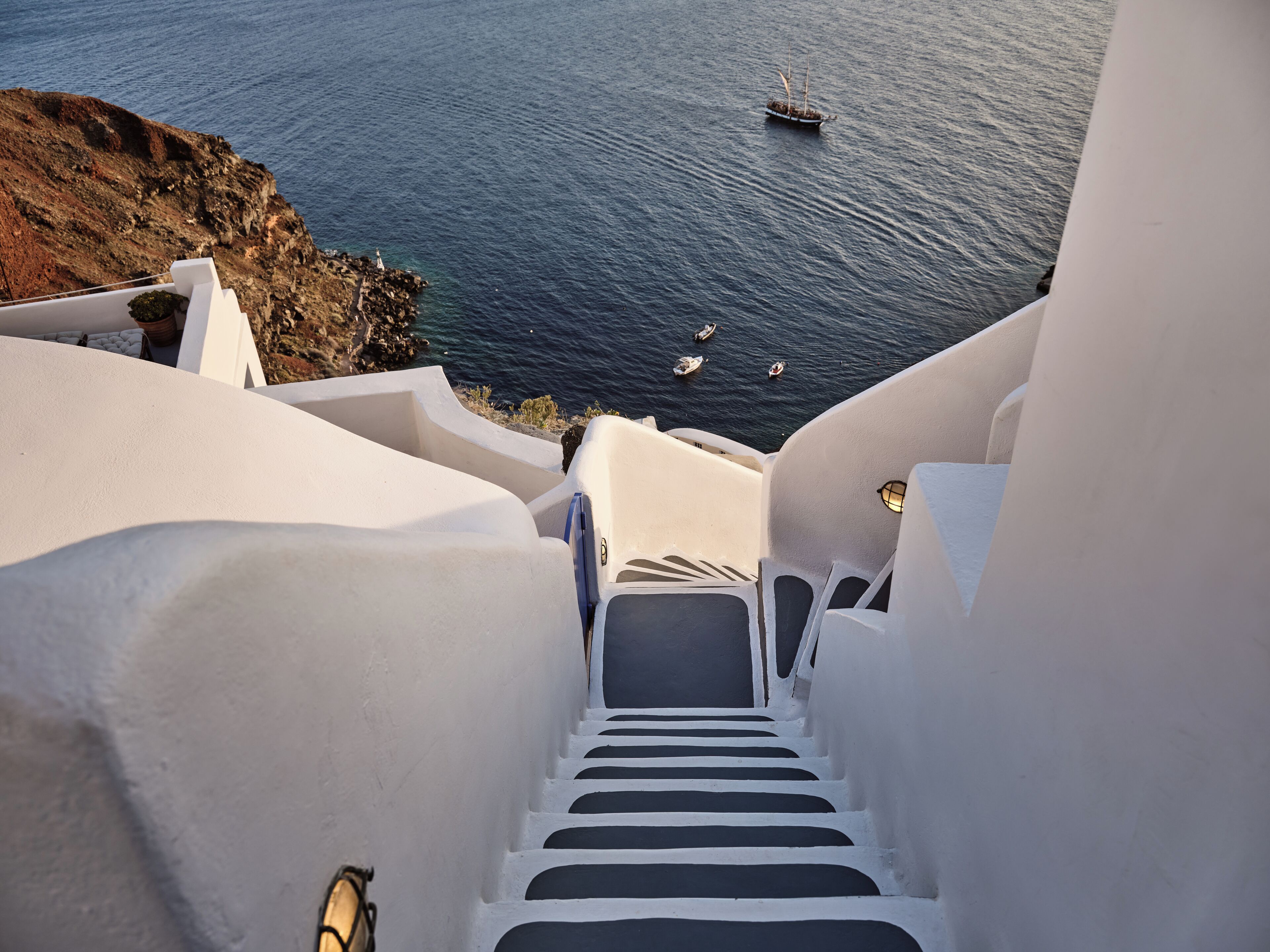 A white staircase leading to a coastal area with boats in the water.