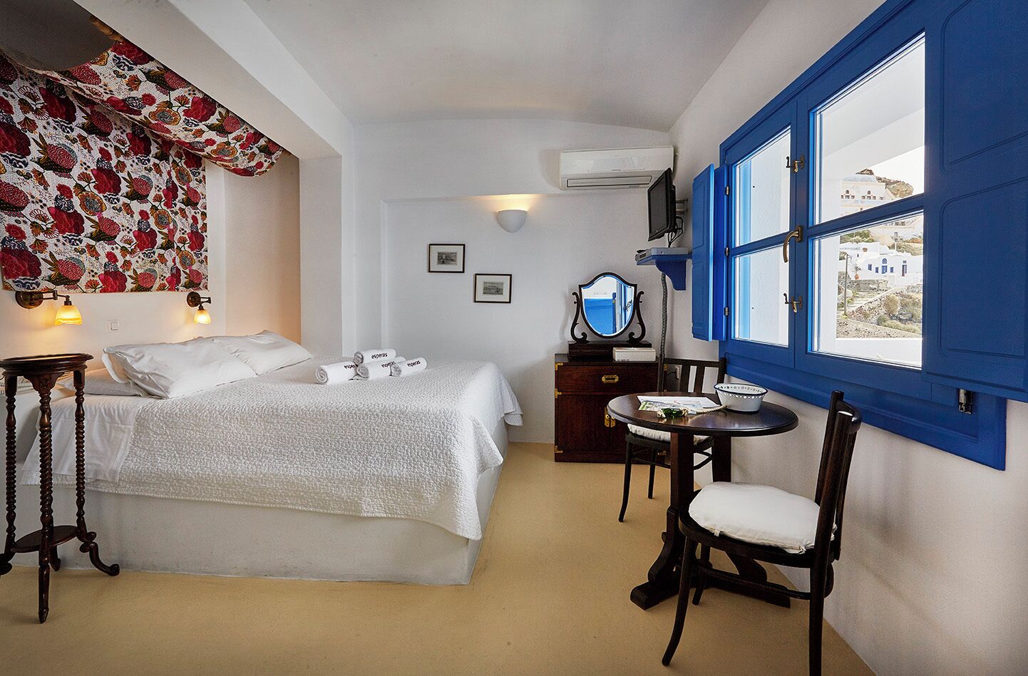 A room with a bed, a small table, a chair, a dresser, and a window with a view.