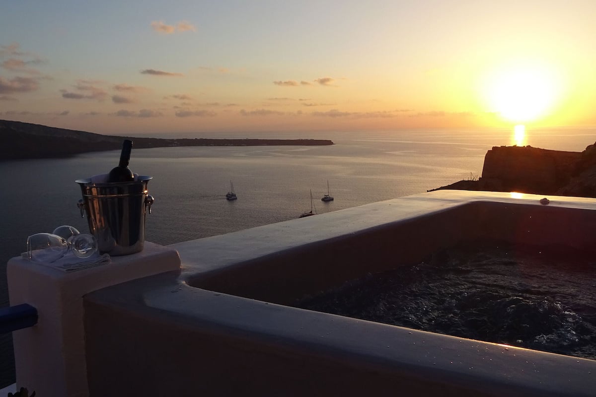 Solnedgangsudsigt fra en balkon med swimmingpool, en metalspand og glas på kanten.