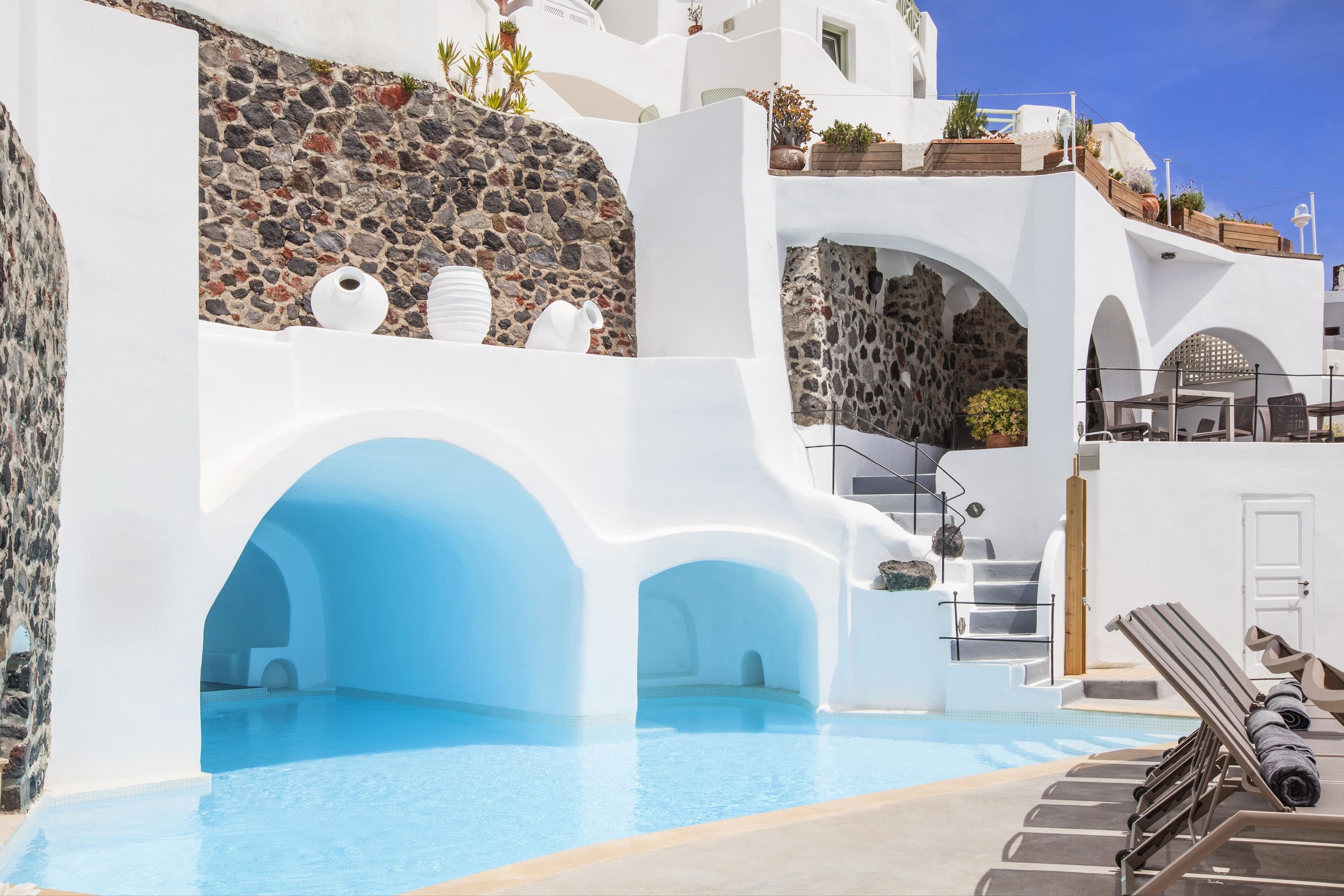 Een buitenzwembad, parasols bij het zwembad en ligstoelen