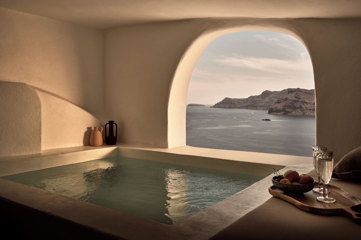 Spa-område med havudsigt, et badekar og en bakke med frugt og glas.