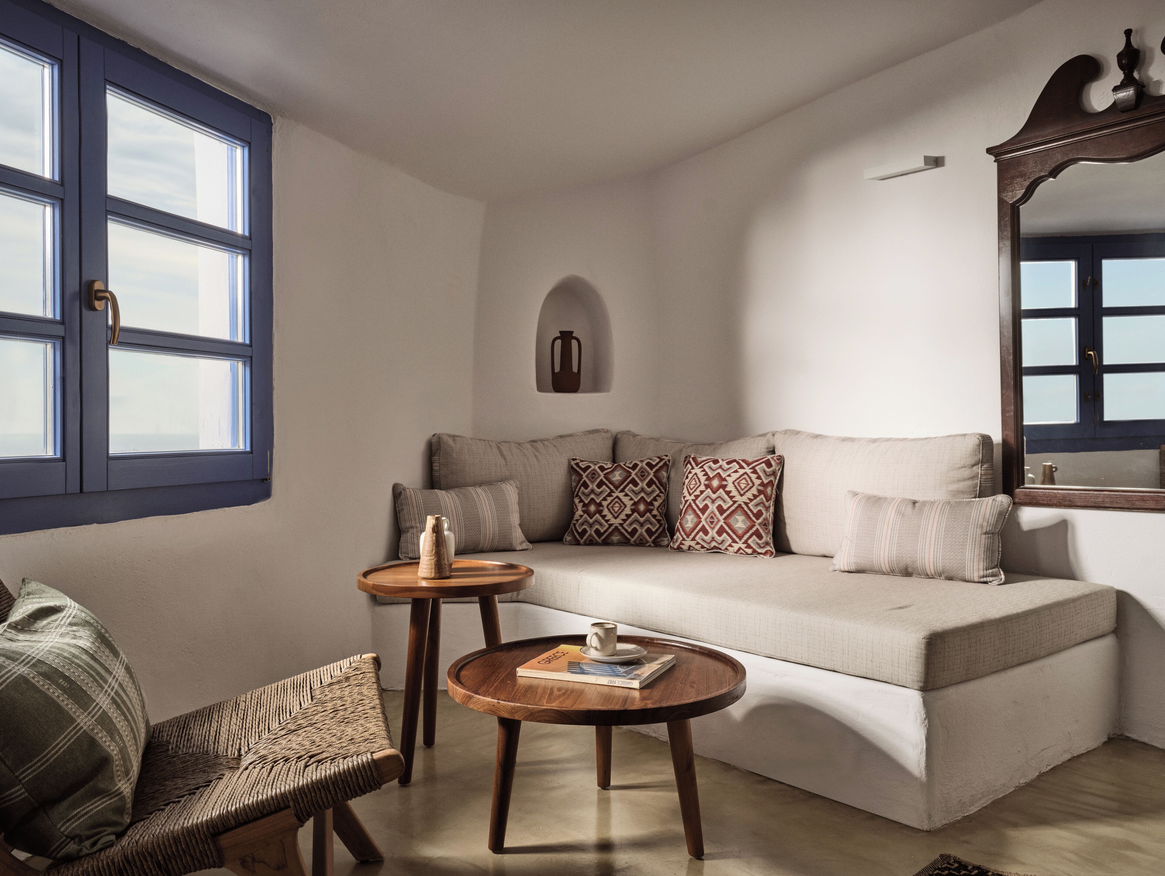 A living room with a sofa, two side tables, a chair, and a mirror.