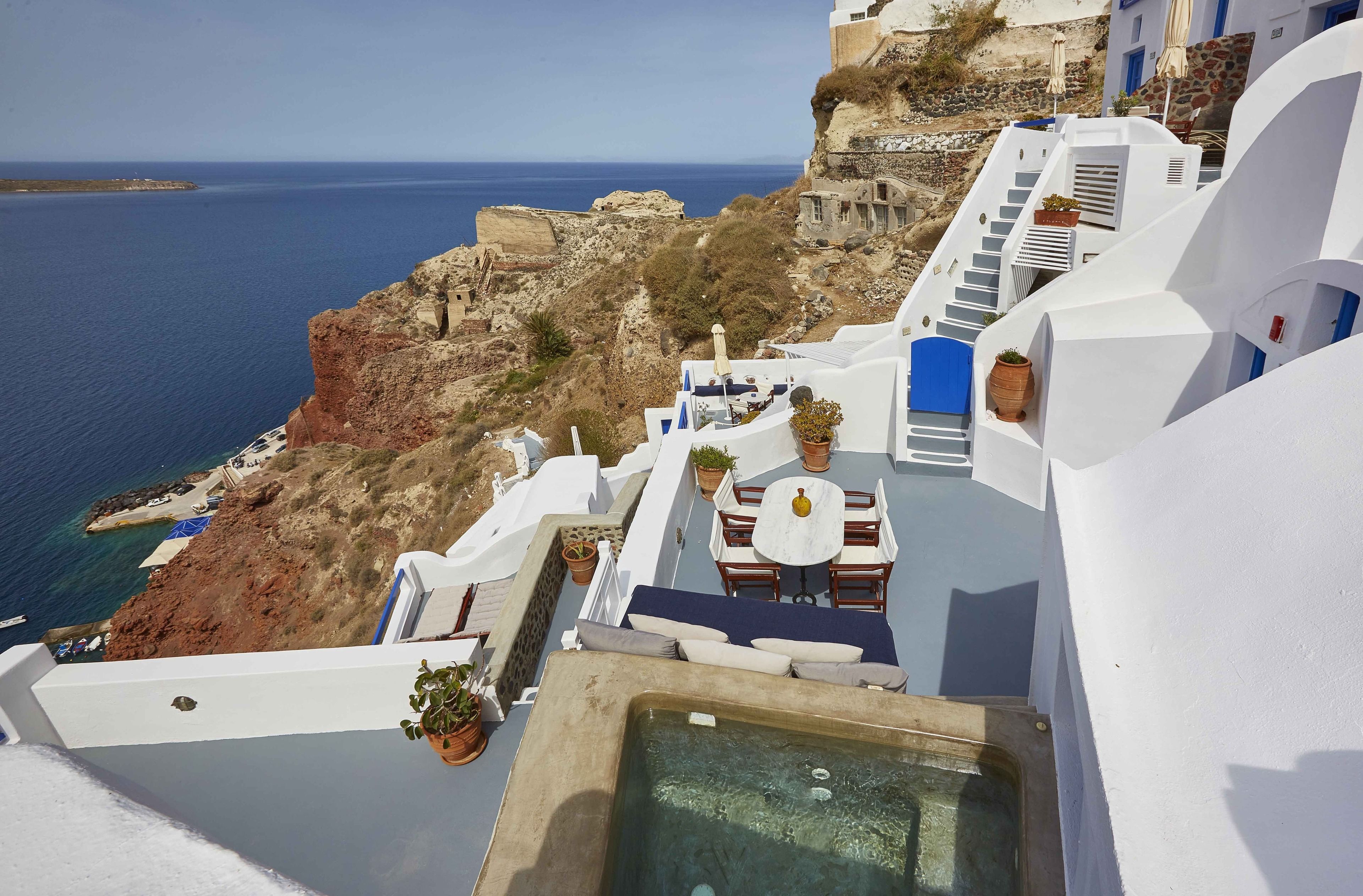 A seaside hotel with a pool, outdoor seating, and a view of the sea.