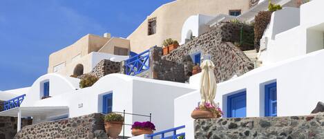 A white building with blue accents, stone walls, and potted plants.