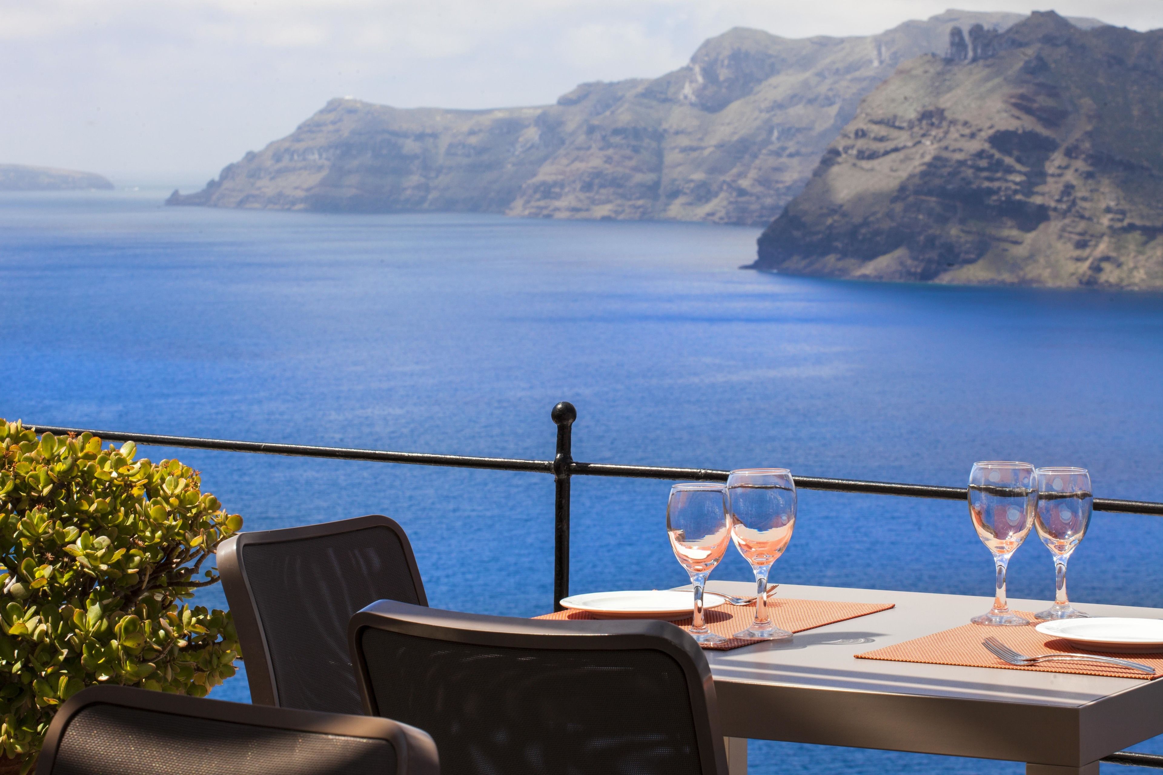 Una mesa para dos con vista al mar y a las montañas.
