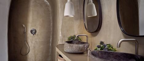 A bathroom with a stone sink, a mirror, and a shower.
