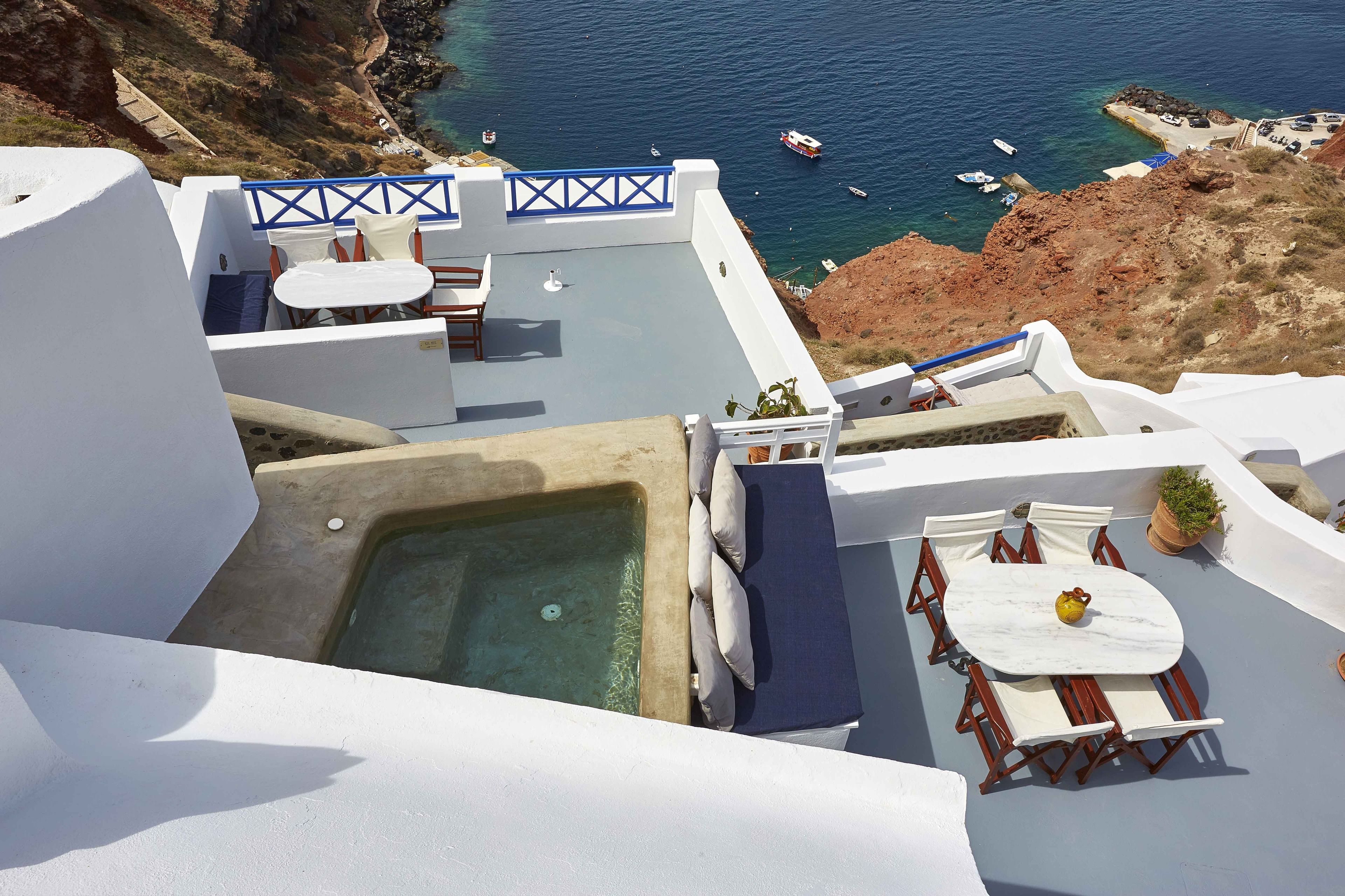 A rooftop terrace with a hot tub, outdoor seating, and a view of the sea.