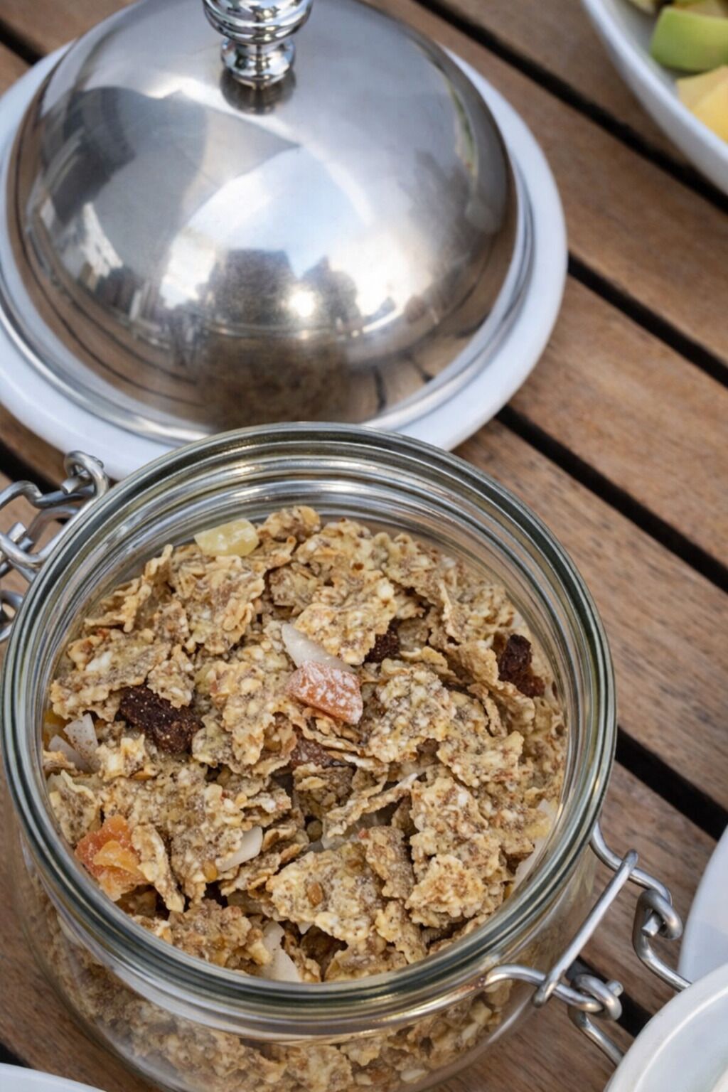 A glass jar filled with granola on a wooden table.