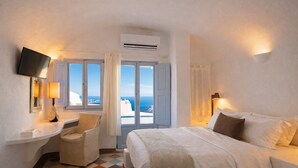 Habitación de hotel con una cama, un escritorio con lámpara, una silla y un televisor.