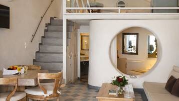 Un vaste espace de vie comprenant une table à manger, des chaises, un canapé, une table basse et un escalier menant à un niveau supérieur.