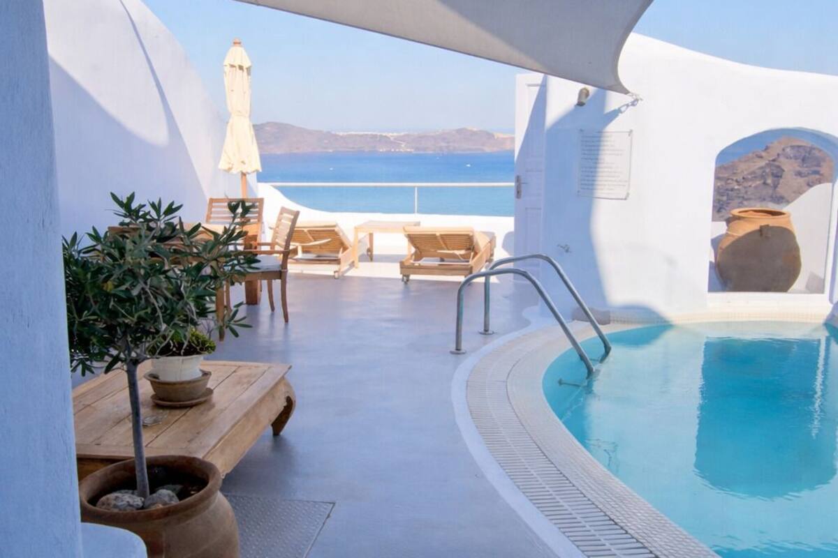 A pool area with lounge chairs and a view of the sea.