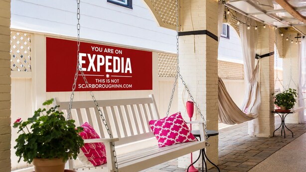 A bench with a sign, a potted plant, and a hanging light fixture.