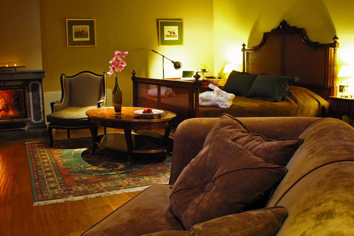 Ein gemütliches Wohnzimmer mit Kamin, einer Couch, einem Sessel und einem Couchtisch.