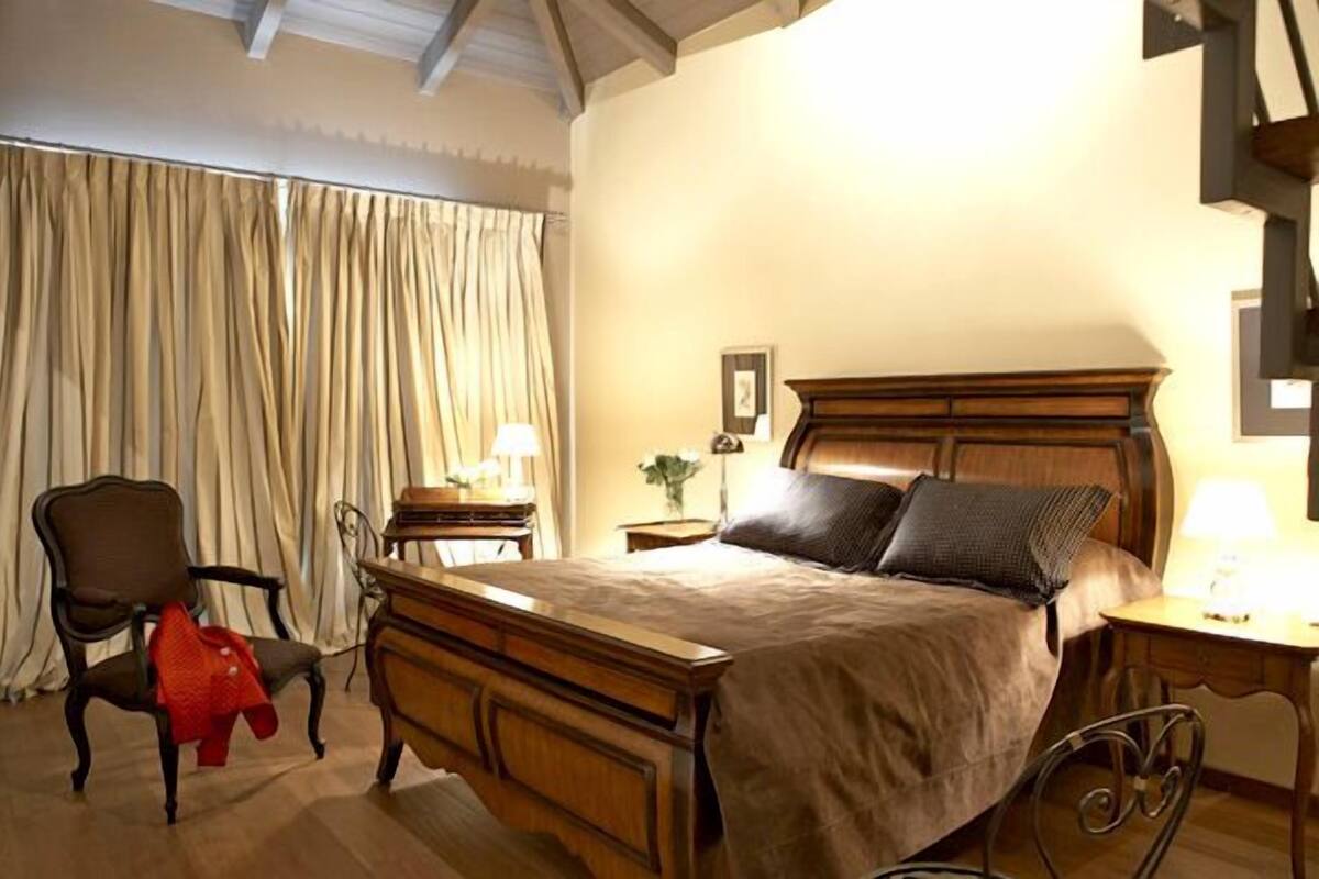 Ein Schlafzimmer mit einem Holzbett, einem Sessel, einem Schreibtisch und einer Lampe.
