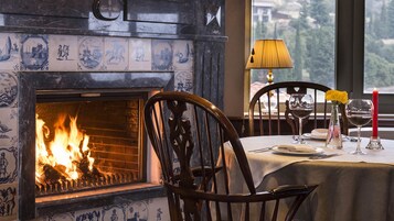 Un comedor con chimenea, una mesa preparada para dos personas y vistas al exterior.