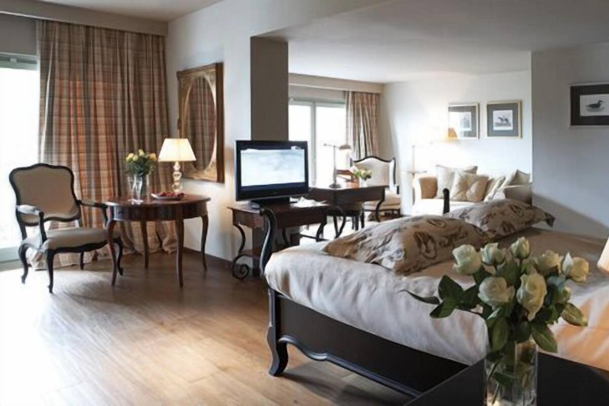 Ein Hotelzimmer mit Bett, Schreibtisch, Fernseher, Stuhl und Lampe.